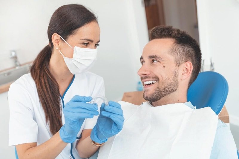 Dentist shows clear aligner to patients.